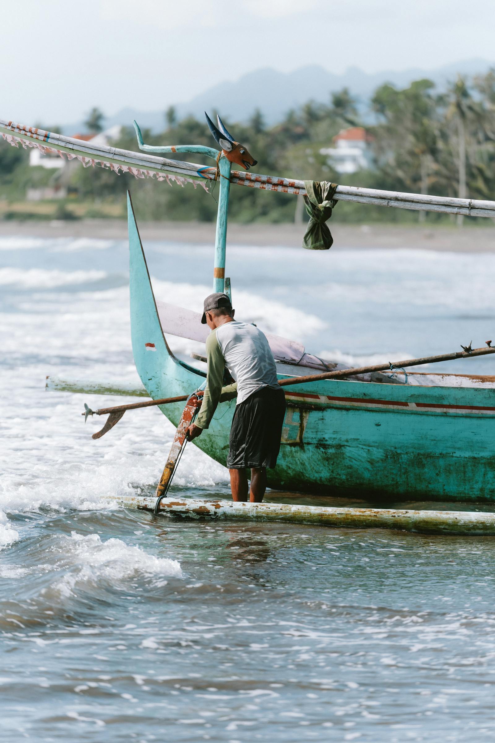 Fisherman preparing a boat in the surf at the shoreline.